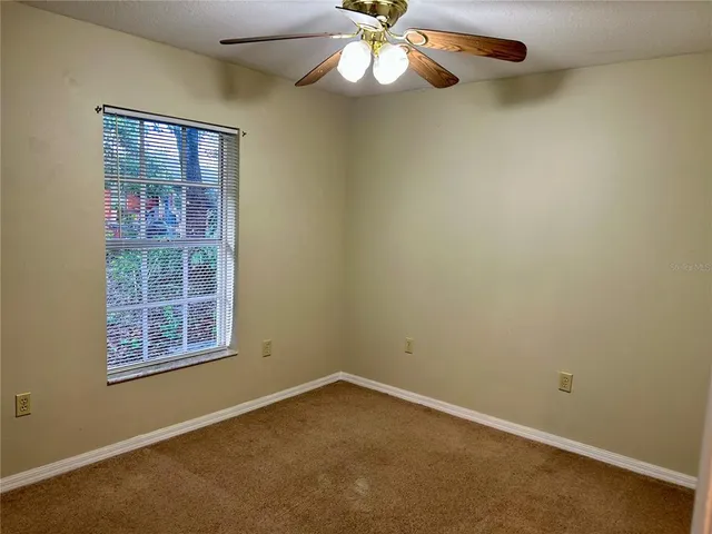 an empty room with windows and fan