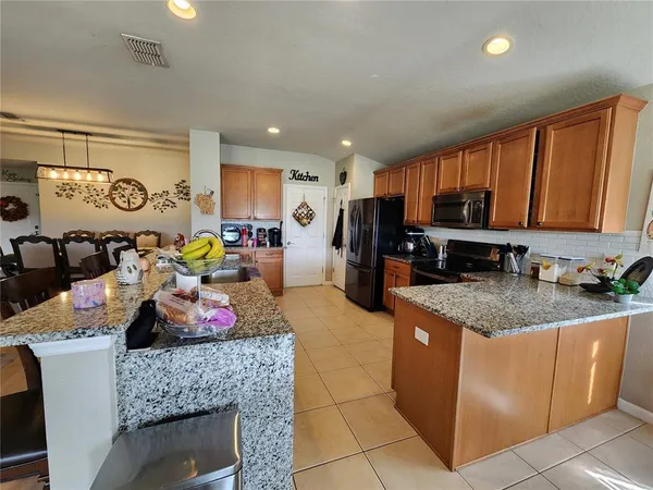 a kitchen with stainless steel appliances granite countertop a sink dishwasher stove and refrigerator with wooden cabinets