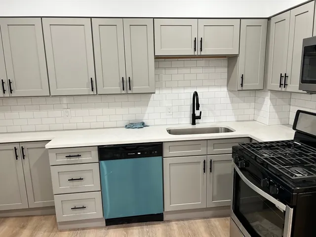 a kitchen with granite countertop white cabinets and stainless steel appliances