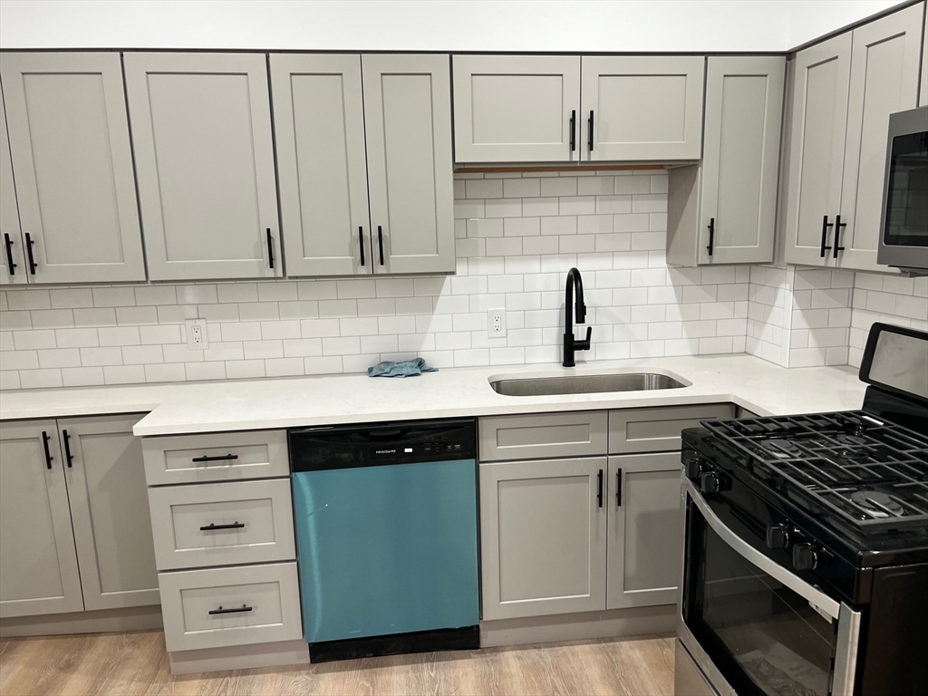 72 Bloomingdale Street, Unit 1 Chelsea, MA 02150 - Photo 2 of 6 a kitchen with granite countertop white cabinets and stainless steel appliances