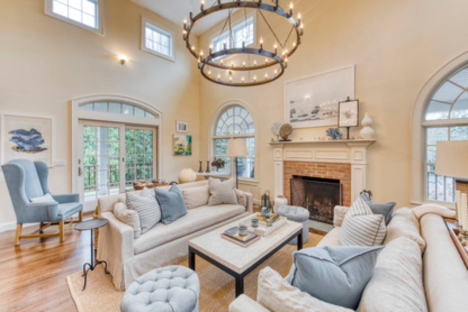 a living room with furniture a fireplace a large window and a chandelier