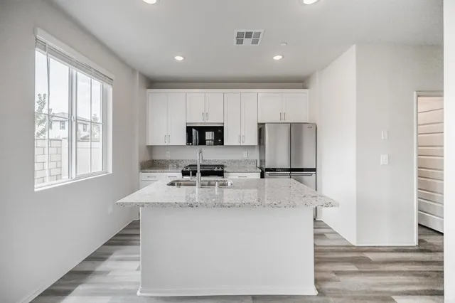 a kitchen with kitchen island granite countertop a sink appliances cabinets and a counter top space