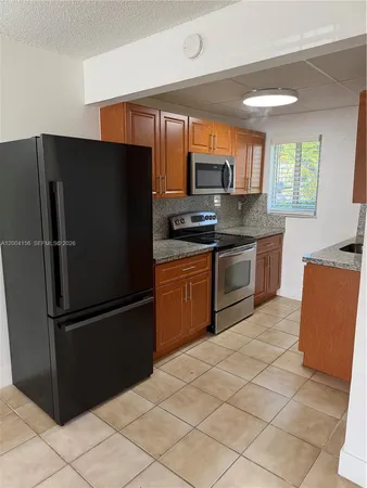 a kitchen with stainless steel appliances granite countertop a refrigerator and a stove top oven