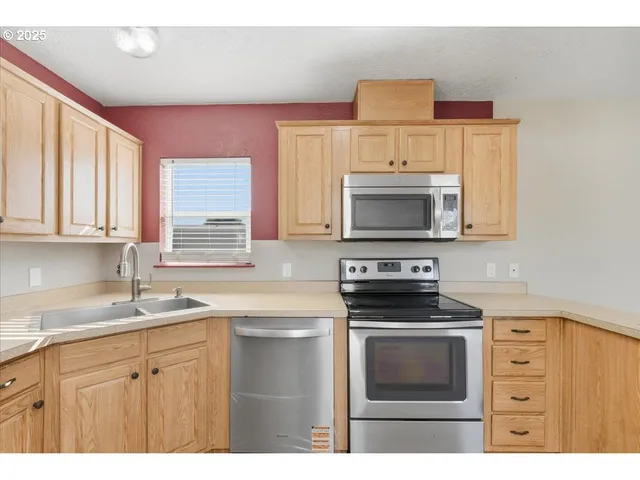 a kitchen with cabinets stainless steel appliances and a window