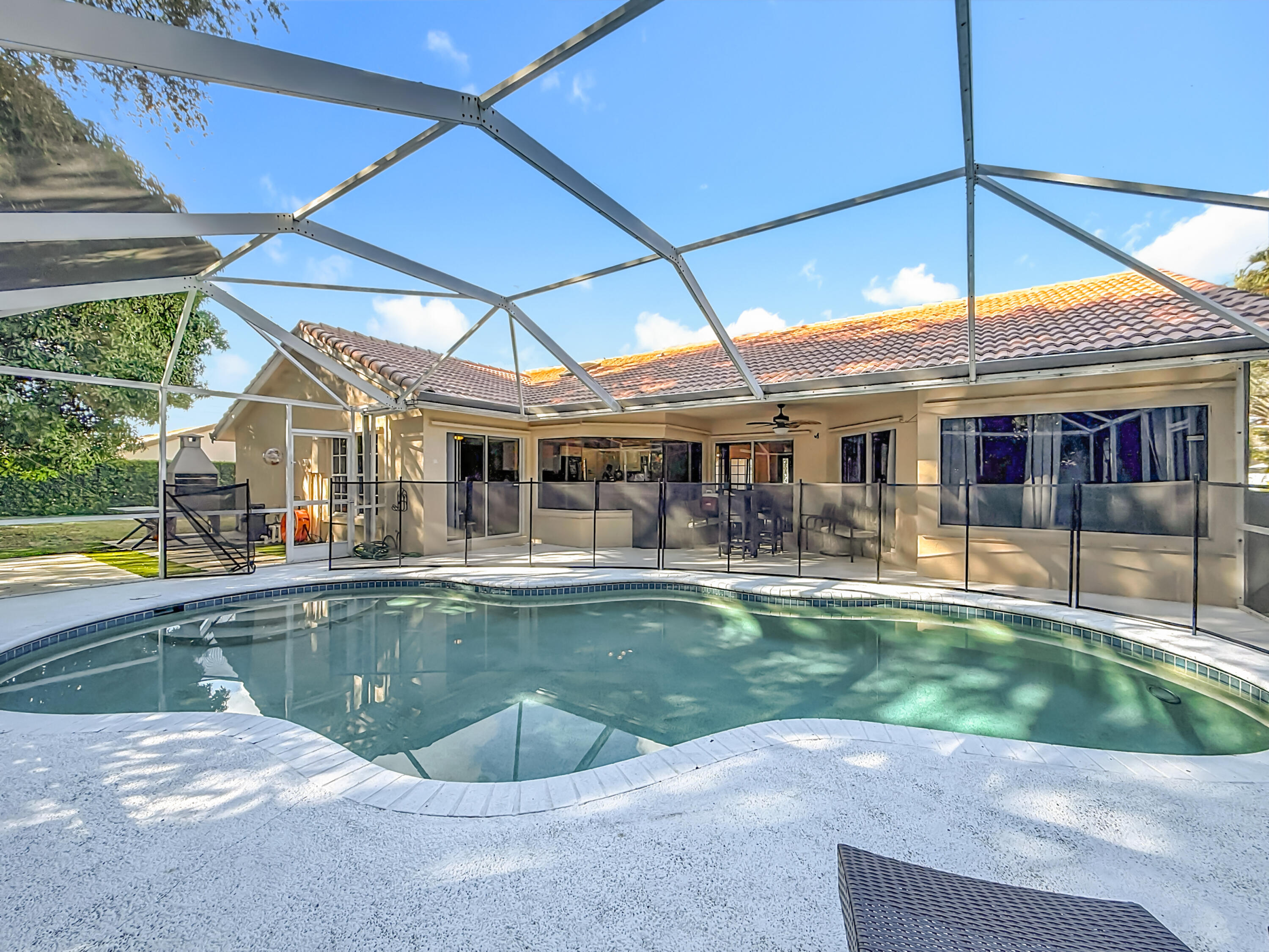 450 Northwest 53rd Street Boca Raton, FL 33487 - Photo 36 of 52 a view of a house with pool fire pit tables and chairs under an umbrella