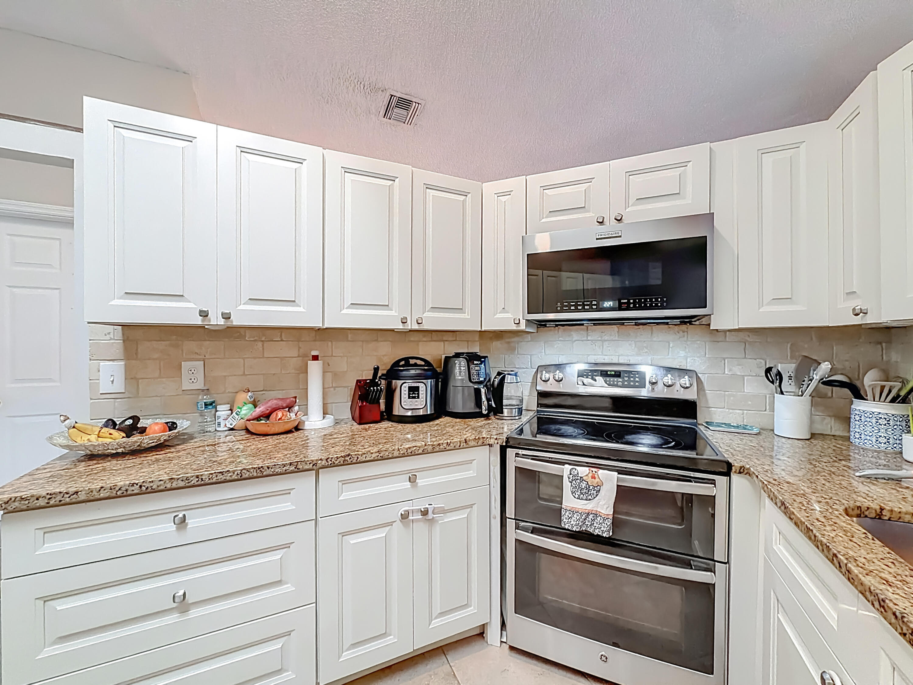 450 Northwest 53rd Street Boca Raton, FL 33487 - Photo 9 of 52 a kitchen with white cabinets and appliances