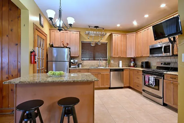 a kitchen with stainless steel appliances granite countertop a sink refrigerator stove and microwave