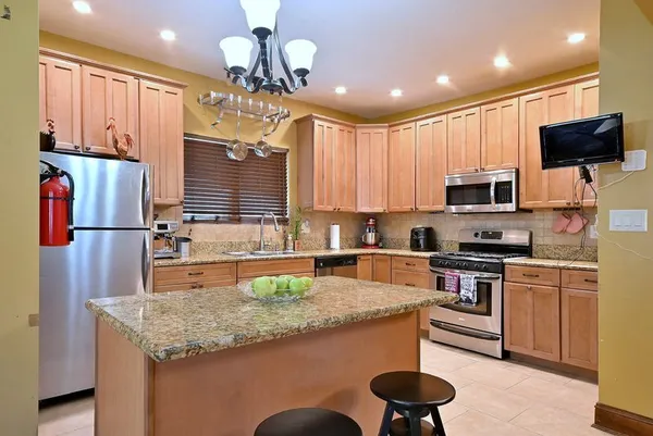a kitchen with kitchen island granite countertop a sink stainless steel appliances and cabinets