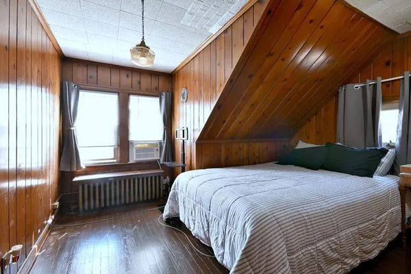 a bedroom with a bed and a large window with wooden floor