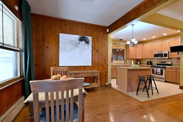 a kitchen with stainless steel appliances kitchen island granite countertop a table chairs sink and cabinets