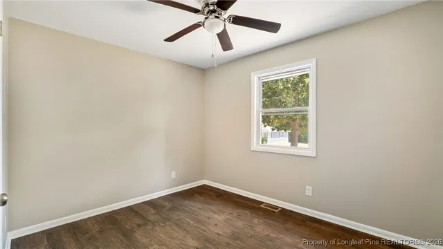 an empty room with a window and a fan