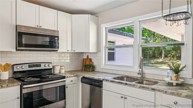 a kitchen with granite countertop a sink a stove and cabinets
