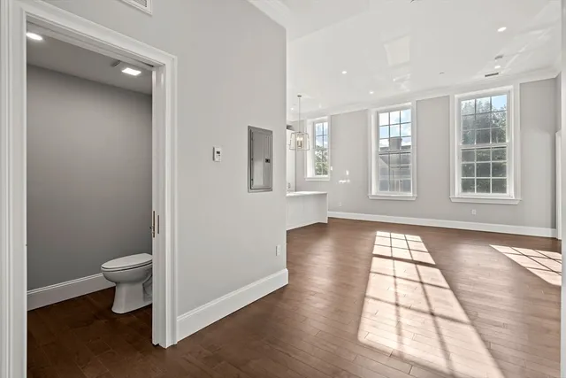 a view of an empty room with a window and wooden floor