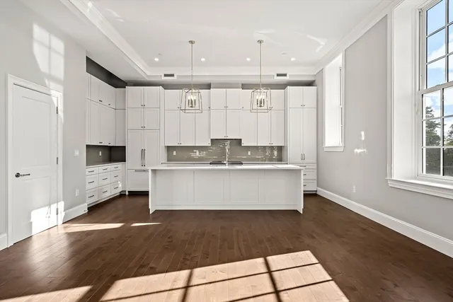 a kitchen with stainless steel appliances kitchen island granite countertop a stove a sink and white cabinets
