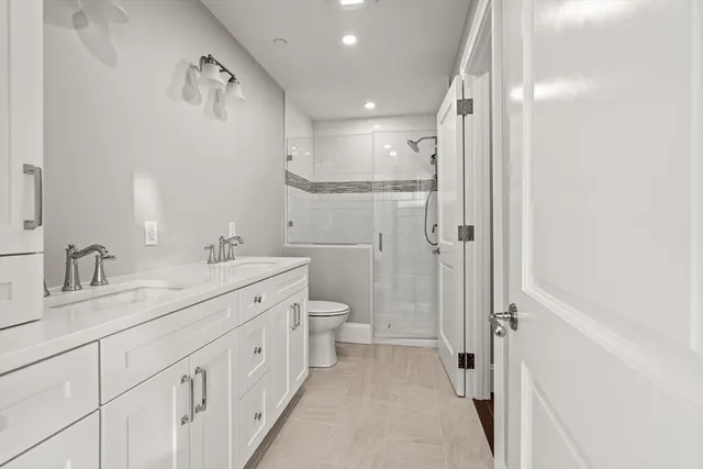 a spacious bathroom with a double vanity sink toilet mirror and shower