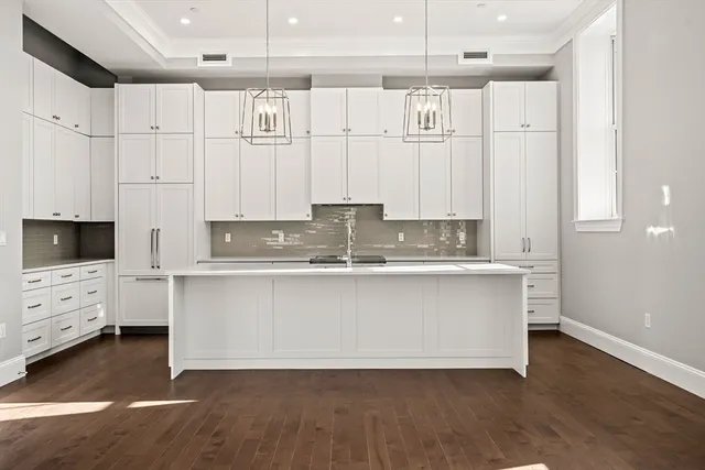 a white kitchen with granite countertop a stove a sink and white cabinets