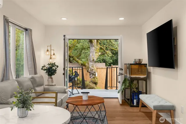 a living room with furniture a large window and wooden floor