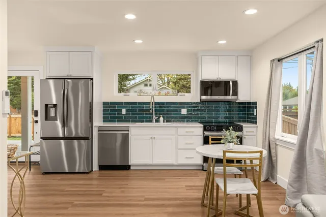 a kitchen with stainless steel appliances wooden floor and a refrigerator