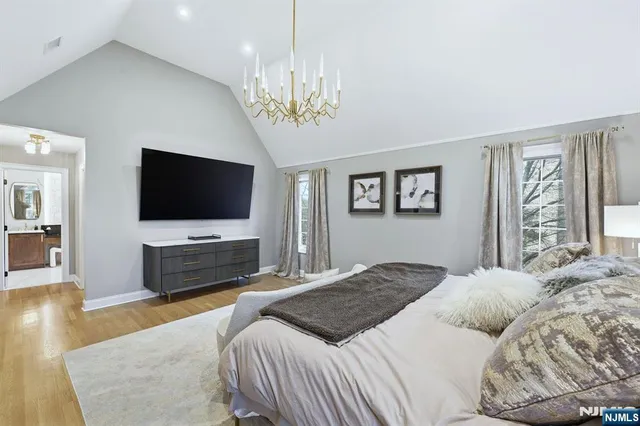 a bedroom with a large bed a flat tv screen and a chandelier