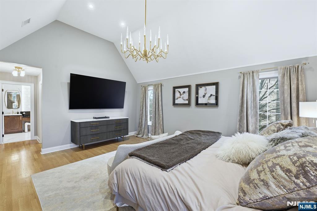 204 Bearwoods Road Park Ridge, NJ 07656 - Photo 17 of 39 a bedroom with a large bed a flat tv screen and a chandelier