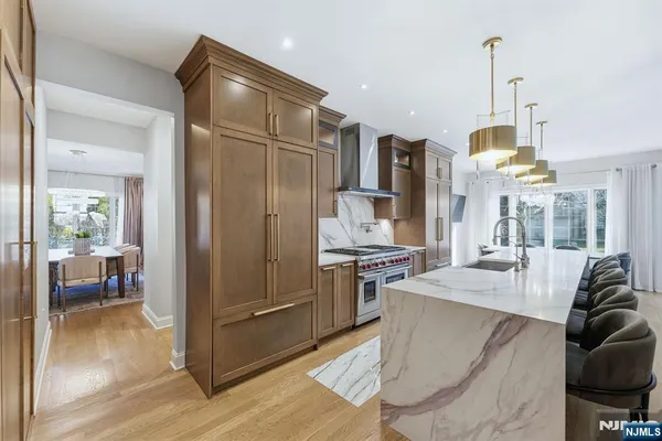 a kitchen with stainless steel appliances kitchen island granite countertop a refrigerator a stove and a sink with wooden floor