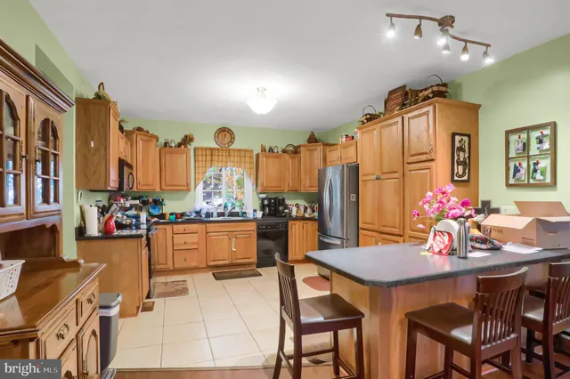 a kitchen with stainless steel appliances kitchen island granite countertop a dining table and chairs in it