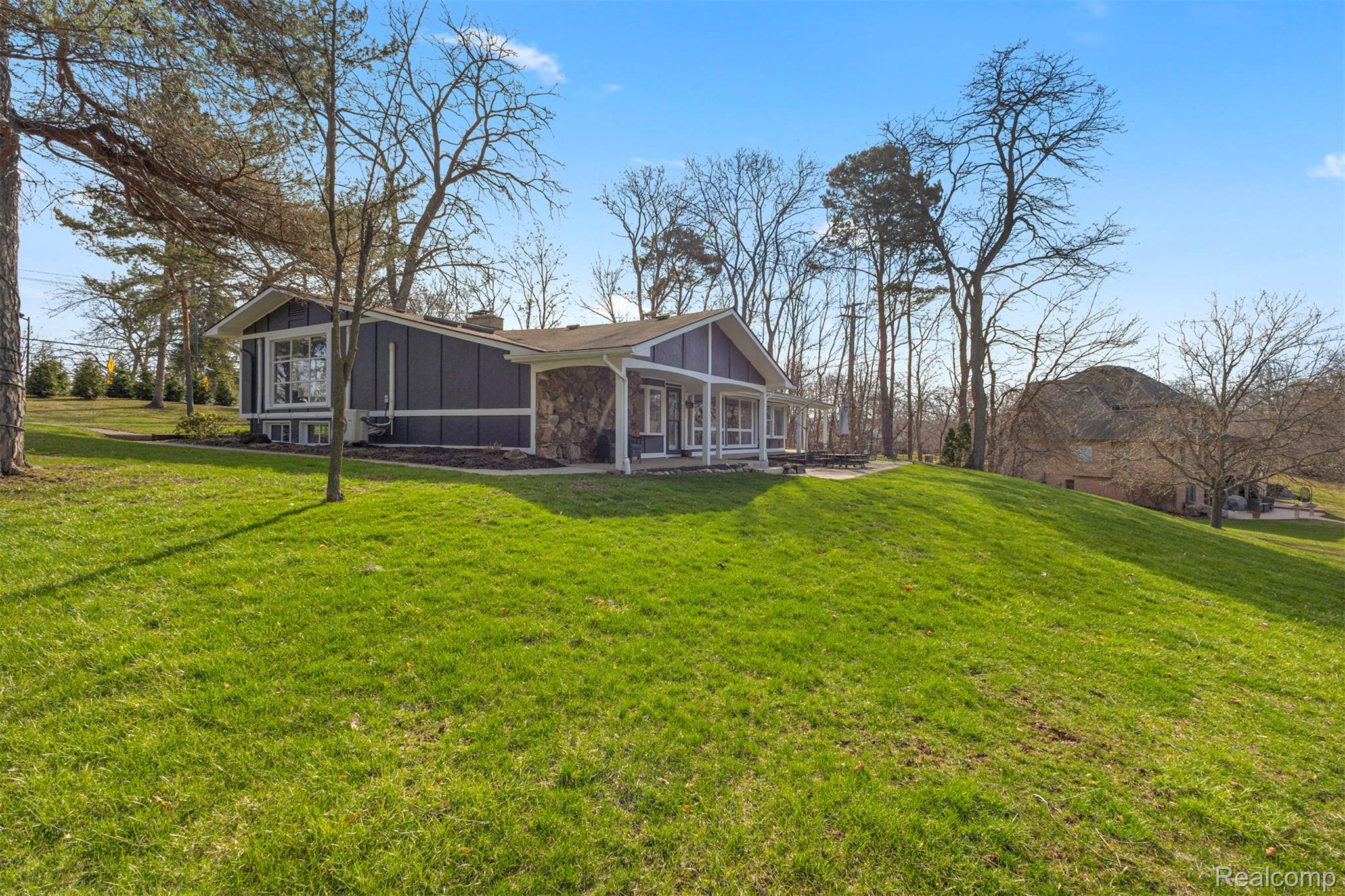 45401 West 9 Mile Road Novi, MI 48374 - Photo 39 of 67 Back of house with board and batten siding, a lawn, and covered porch