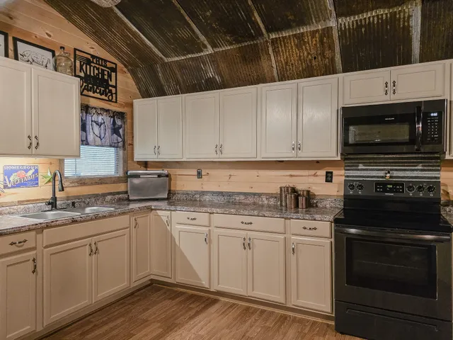 a kitchen with stainless steel appliances granite countertop a stove a sink and white cabinets