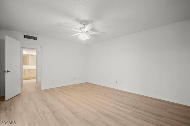 an empty room with wooden floor and fan