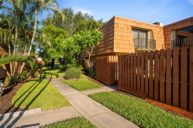 a view of a yard with plants and a large tree