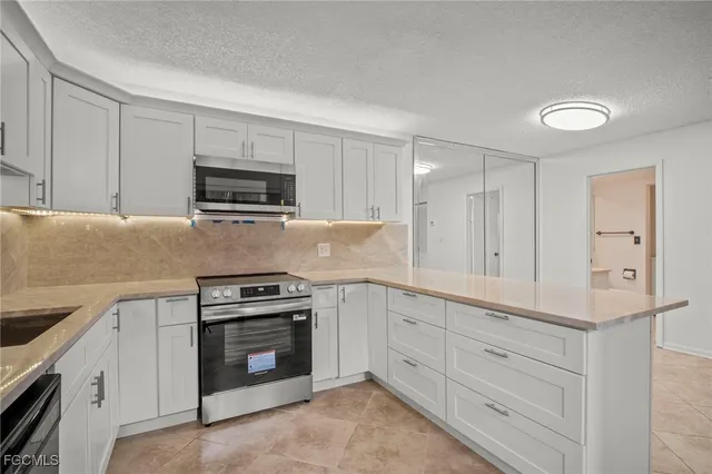 a kitchen with granite countertop white cabinets and stainless steel appliances