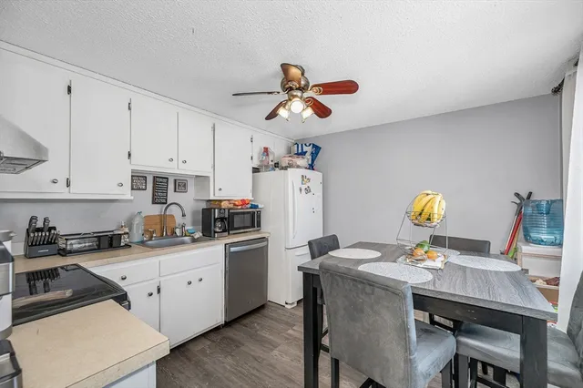 a kitchen with stainless steel appliances granite countertop a stove a sink dishwasher and white cabinets with wooden floor