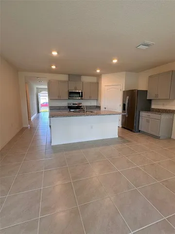 a large kitchen with a large counter top a stove a microwave and a refrigerator