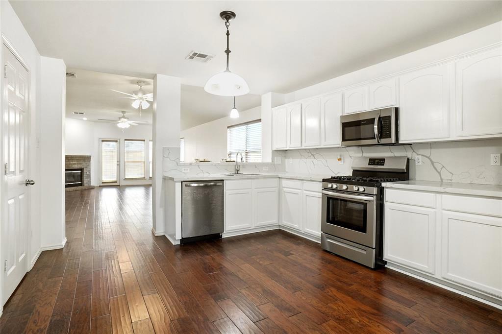 9907 Divine Court Frisco, TX 75033 - Photo 9 of 31 Kitchen featuring tasteful backsplash, stainless steel appliances, hanging light fixtures, white cabinetry, and dark wood finished floors