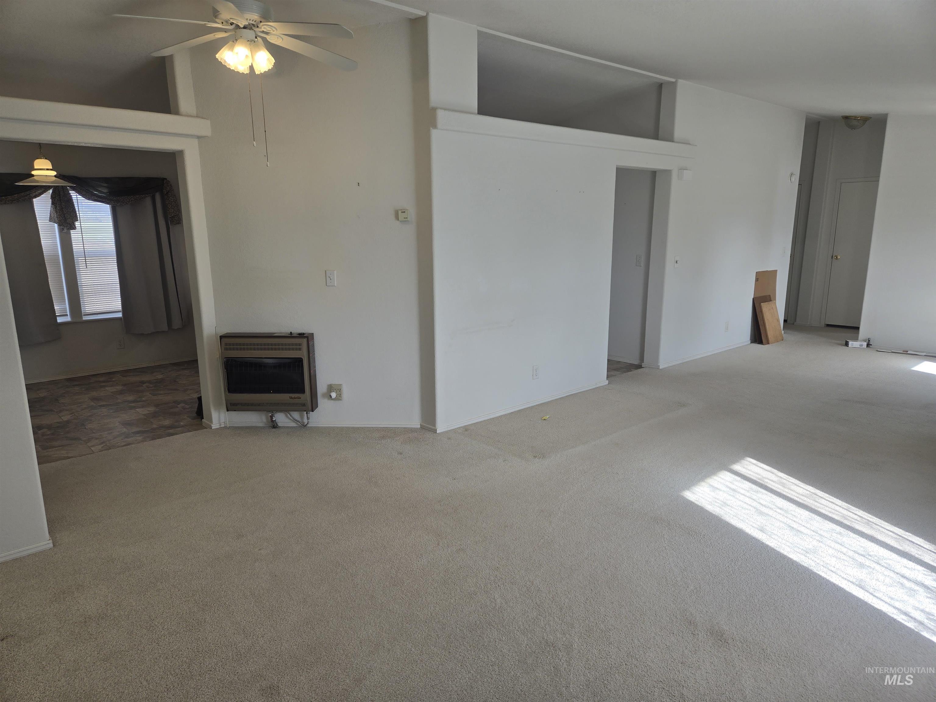 135 Harrisburg Road Kamiah, ID 83536 - Photo 4 of 30 Unfurnished living room with heating unit, ceiling fan, carpet floors, vaulted ceiling, and a fireplace