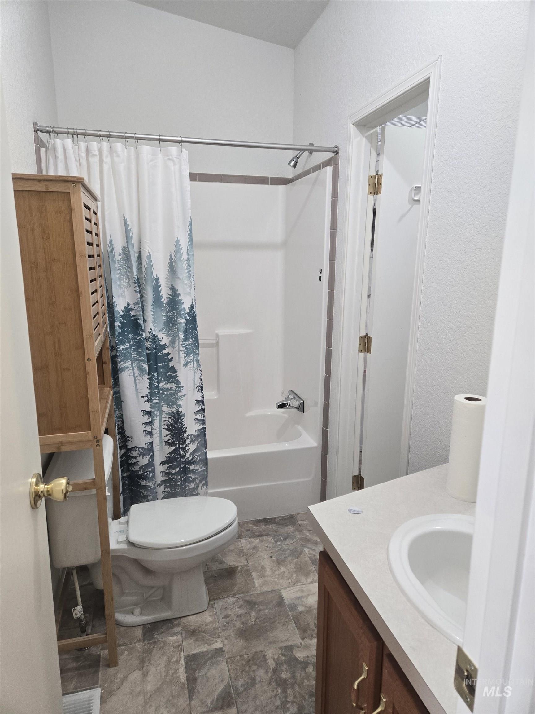 135 Harrisburg Road Kamiah, ID 83536 - Photo 10 of 30 Full bathroom featuring vanity, shower / bath combination with curtain, stone finish flooring, and a textured wall
