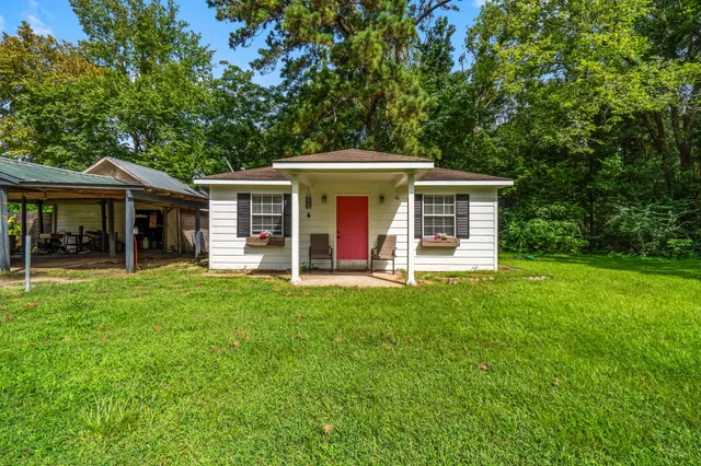 a view of a house with a yard deck and a large tree