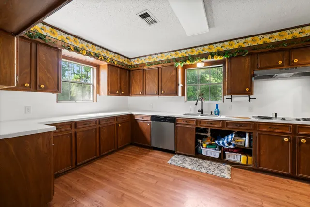 a view of a hallway with wooden floor and a kitchen