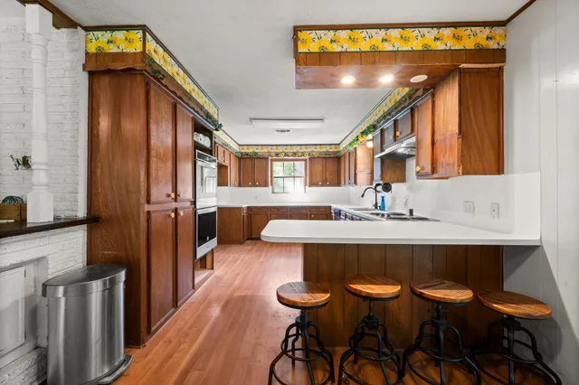 a kitchen with stainless steel appliances kitchen island granite countertop a sink cabinets and wooden floor