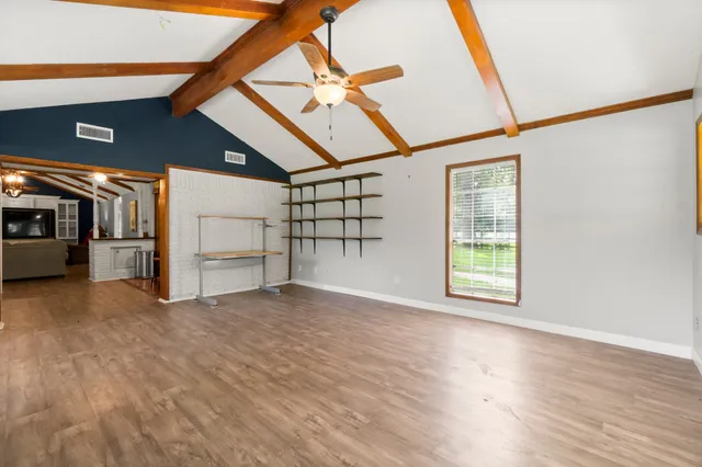 a view of an empty room with a window and a kitchen