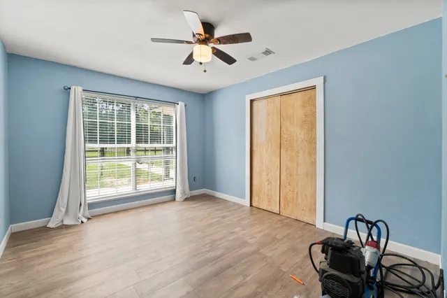 a view of a room with wooden floor and a ceiling fan