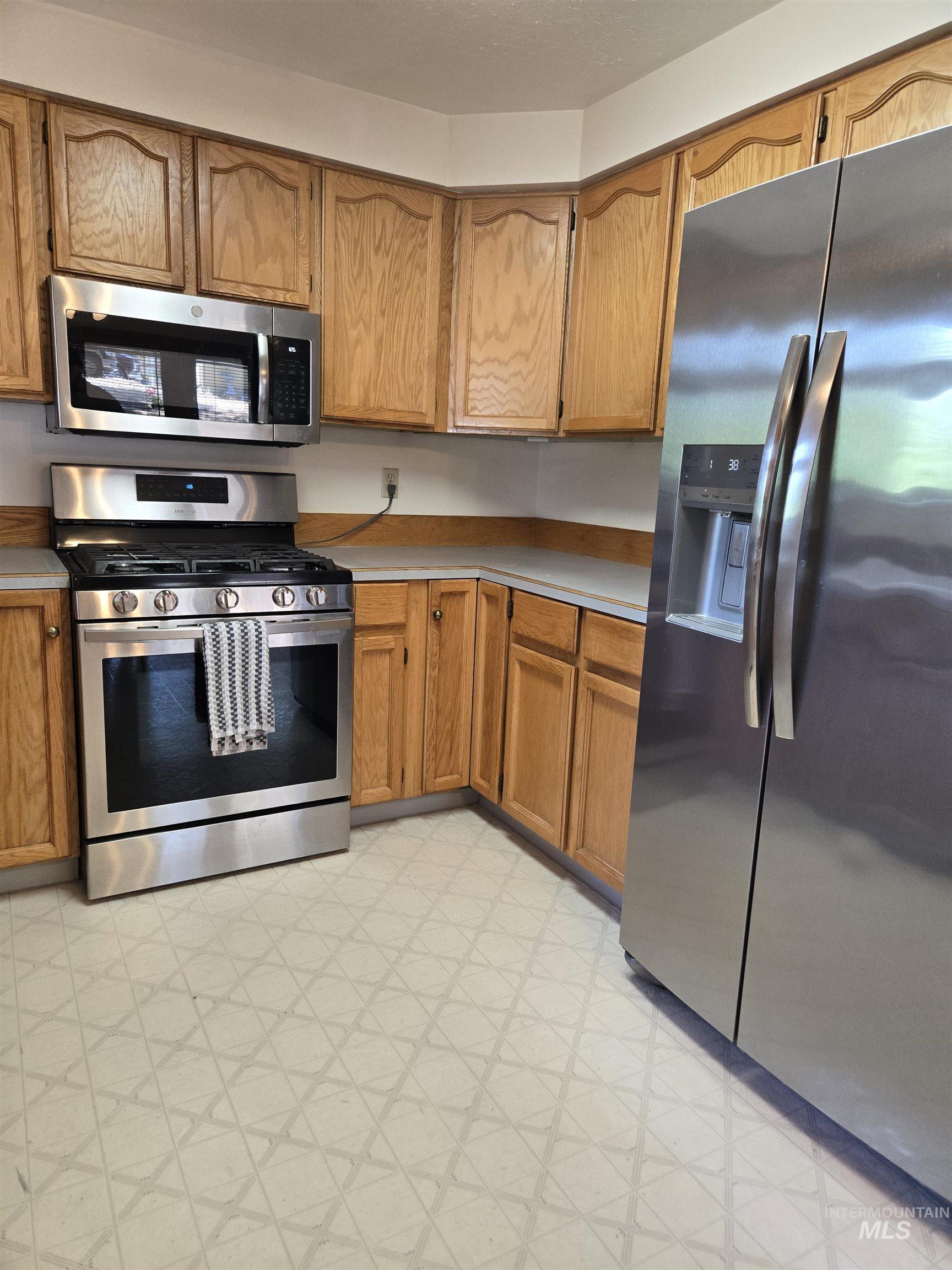 12050 West Hidden Valley Rim Road Boise, ID 83709 - Photo 5 of 39 Kitchen featuring wood cabinetry, stainless steel gas range, stainless steel microwave, stainless steel side-by-side refrigerator, and patterned flooring