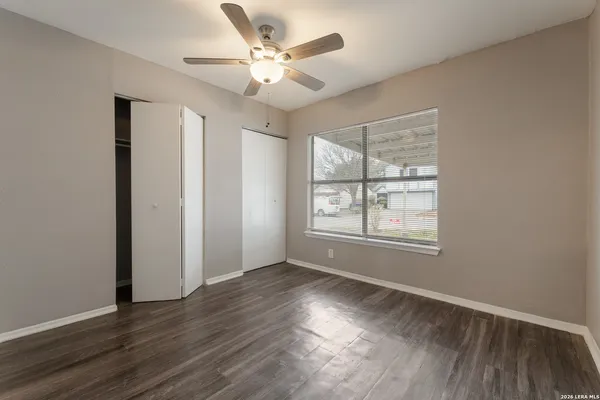 an empty room with wooden floor chandelier fan and windows
