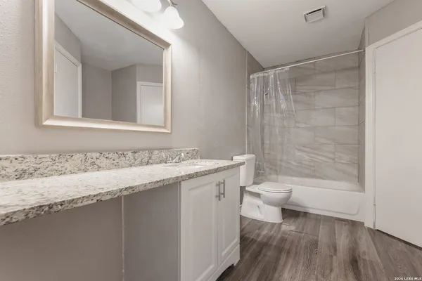 a bathroom with a granite countertop sink a toilet and shower