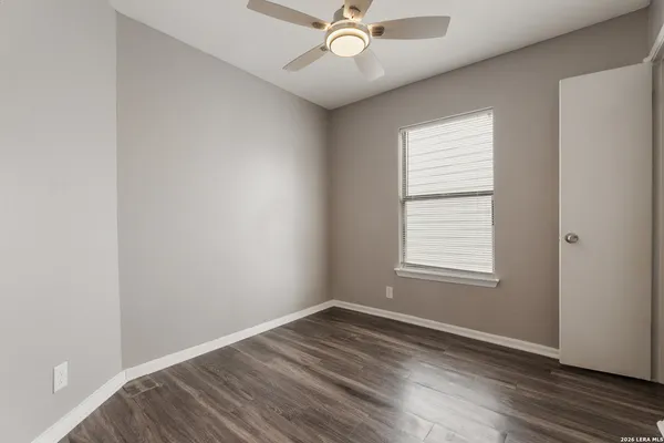an empty room with wooden floor windows and fan