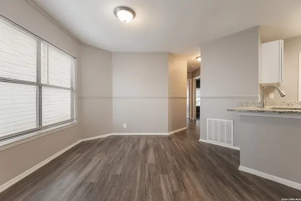 a view of kitchen with a sink wooden cabinets and window