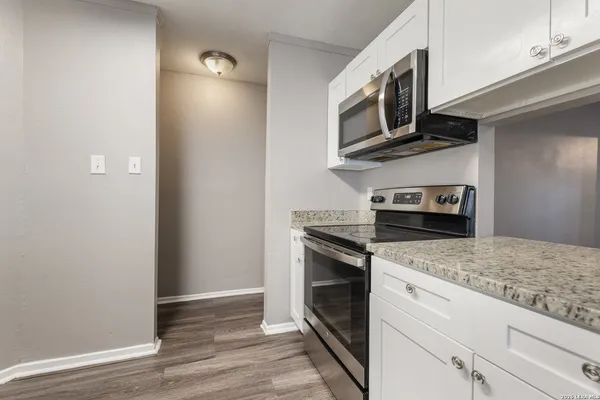 a kitchen with granite countertop cabinets stainless steel appliances and wooden floor