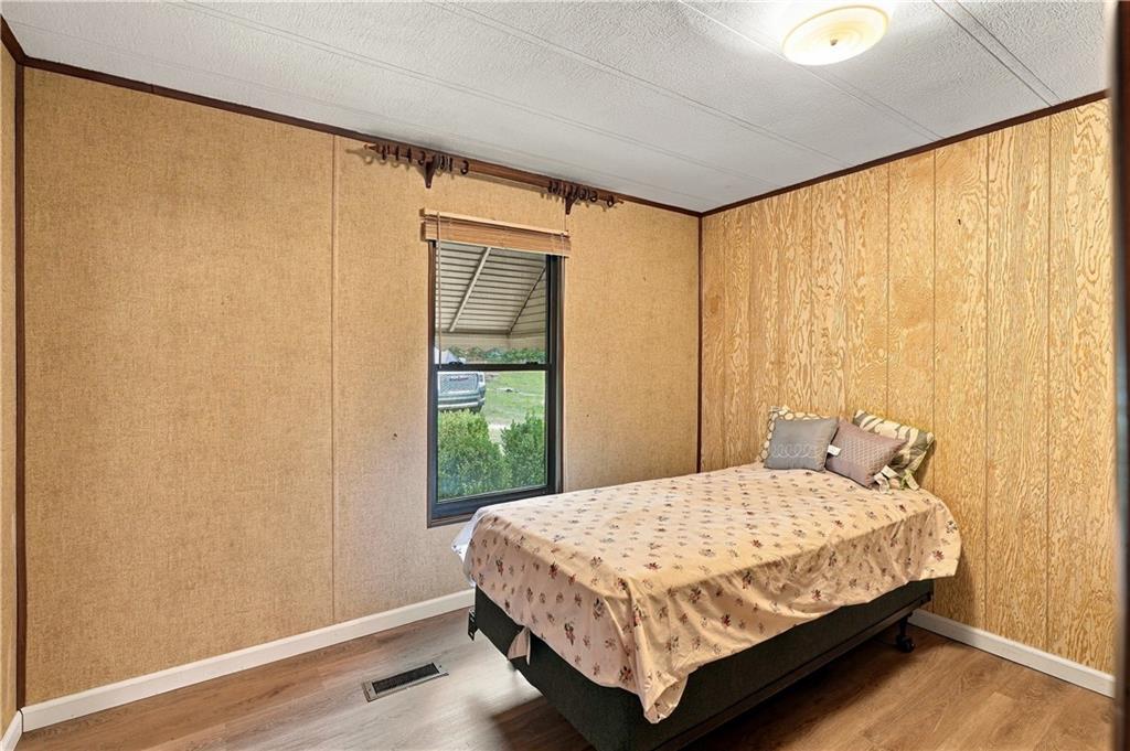 Wood-finish flooring, paneled walls, and a ceiling-mounted light fixture