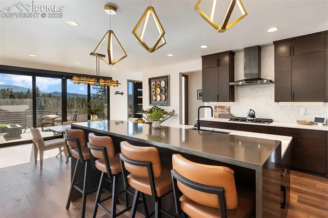 a kitchen with stainless steel appliances granite countertop a stove a sink dishwasher a dining table and chairs with wooden floor