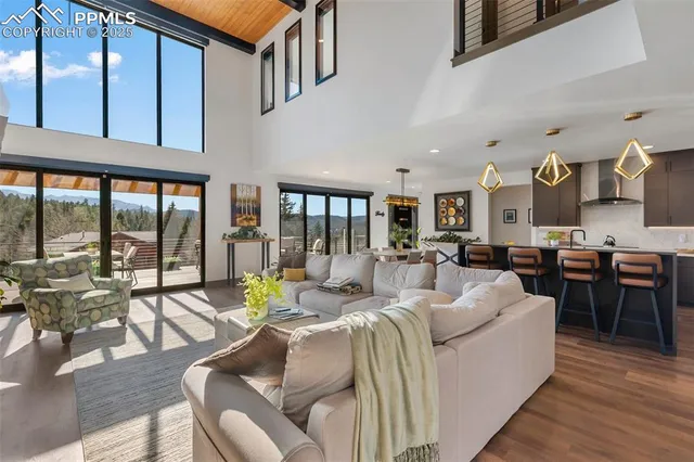 a living room with furniture large windows and wooden floor